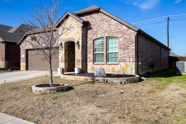 french country home with driveway, central AC unit, an attached garage, and brick siding