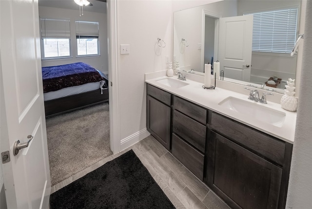 bathroom with baseboards, double vanity, a sink, and connected bathroom