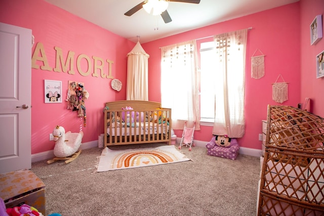 carpeted bedroom with a crib, ceiling fan, and baseboards