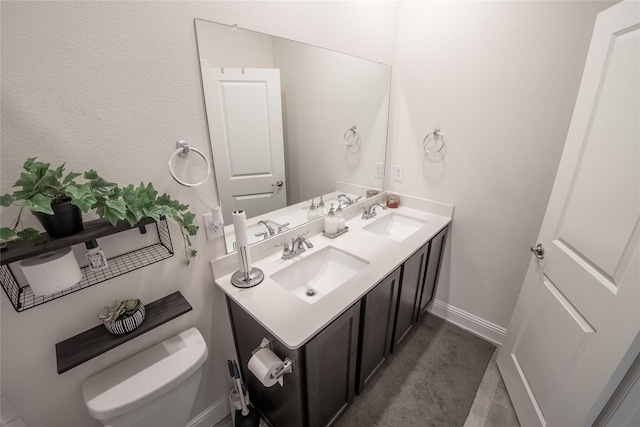 bathroom featuring baseboards, a sink, toilet, and double vanity