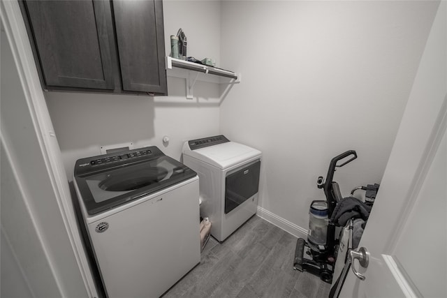 laundry room with cabinet space, washer and clothes dryer, baseboards, and wood finished floors