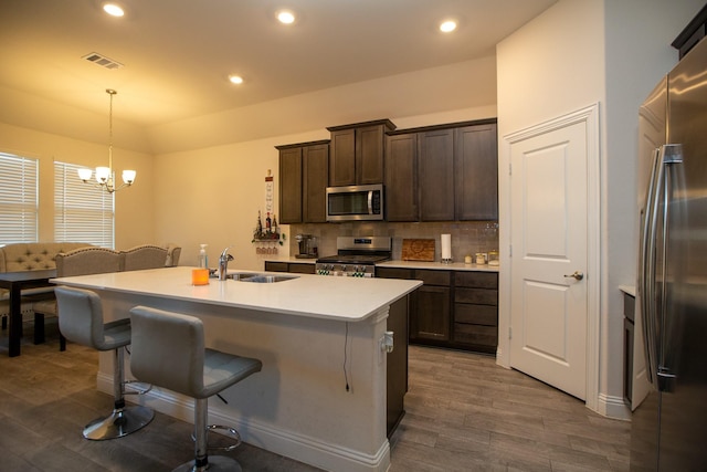 kitchen with dark wood finished floors, a breakfast bar area, visible vents, appliances with stainless steel finishes, and a sink