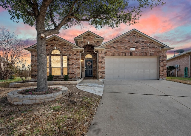 view of front of house featuring driveway, brick siding, and an attached garage