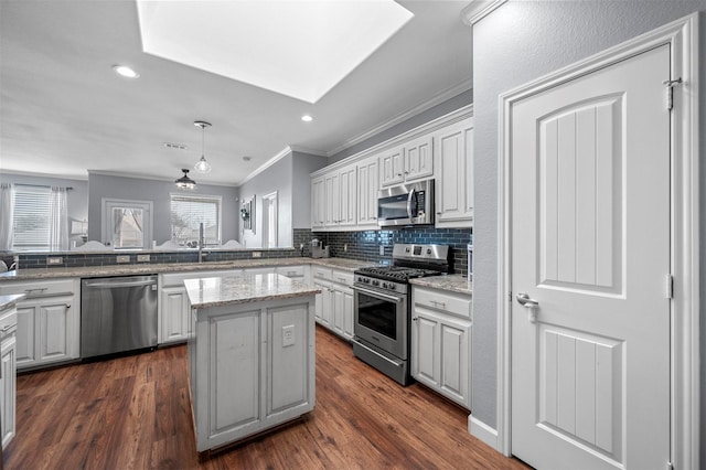 kitchen featuring dark wood-style flooring, crown molding, stainless steel appliances, backsplash, and a kitchen island