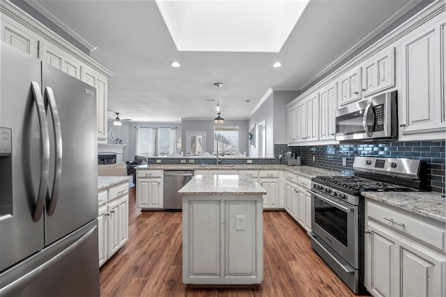 kitchen featuring a peninsula, appliances with stainless steel finishes, a sink, and decorative backsplash