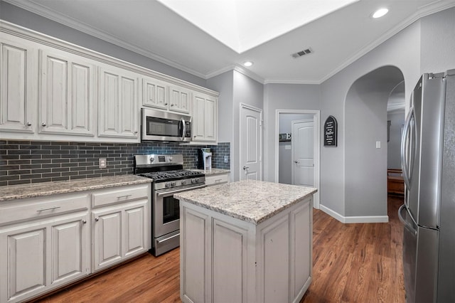 kitchen with arched walkways, tasteful backsplash, visible vents, appliances with stainless steel finishes, and wood finished floors