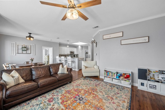 living room with visible vents, baseboards, a ceiling fan, wood finished floors, and crown molding