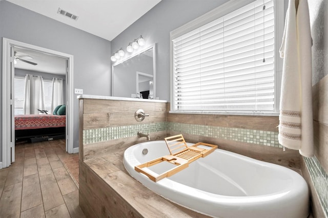 ensuite bathroom featuring a bath, wood finished floors, connected bathroom, and visible vents