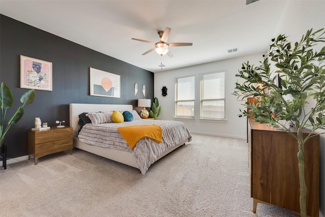 bedroom with light carpet, ceiling fan, visible vents, and baseboards