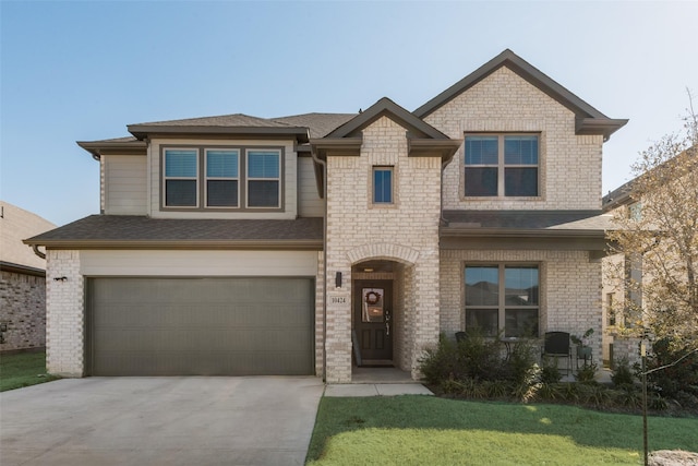 view of front facade featuring driveway, brick siding, roof with shingles, an attached garage, and a front yard