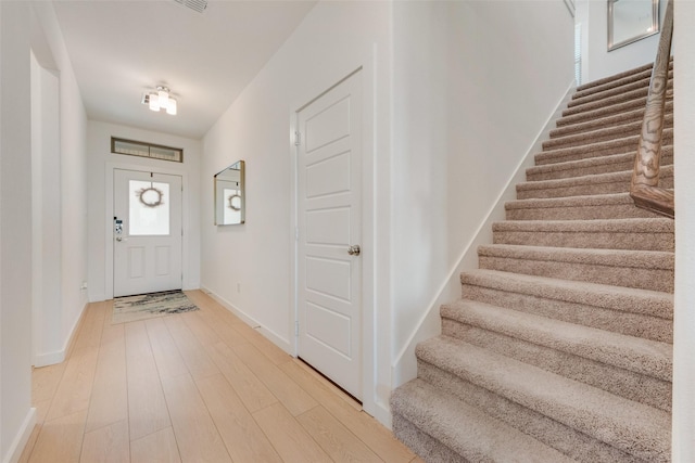 entrance foyer featuring light wood-type flooring, stairs, and baseboards