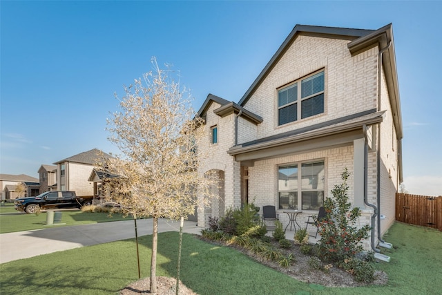 view of front facade featuring driveway, a front yard, fence, and brick siding