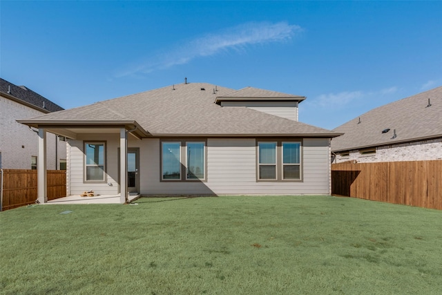 rear view of house featuring a shingled roof, a patio area, a fenced backyard, and a yard