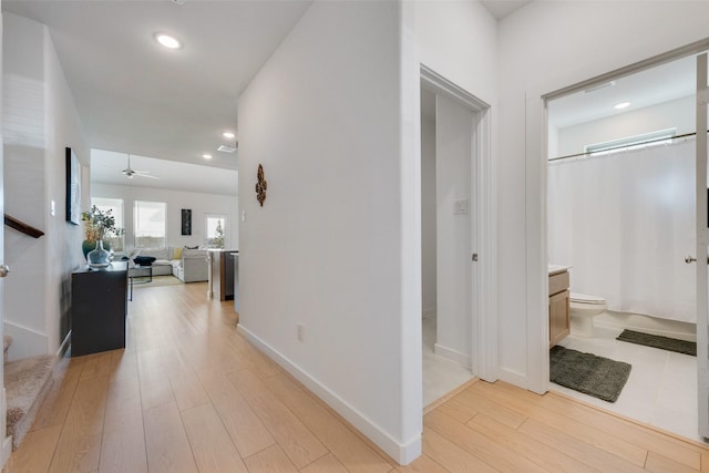 corridor with light wood-style floors, stairs, baseboards, and recessed lighting