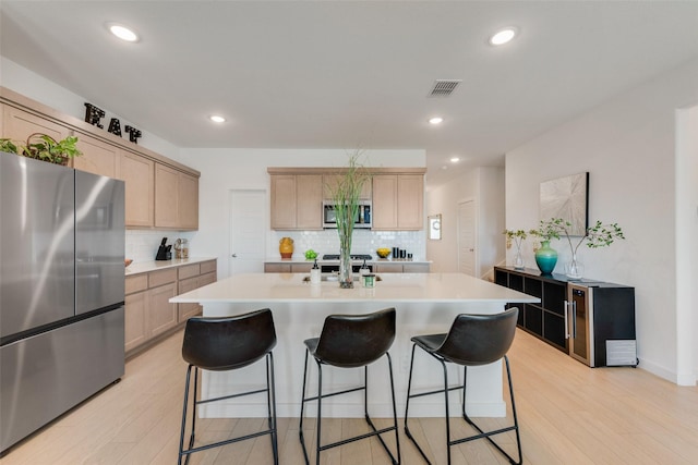 kitchen with a center island with sink, a breakfast bar area, light countertops, visible vents, and appliances with stainless steel finishes