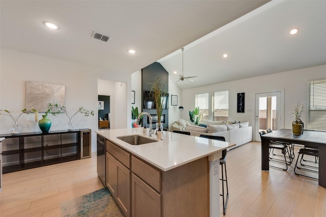 kitchen featuring lofted ceiling, light countertops, visible vents, light wood-style floors, and a sink