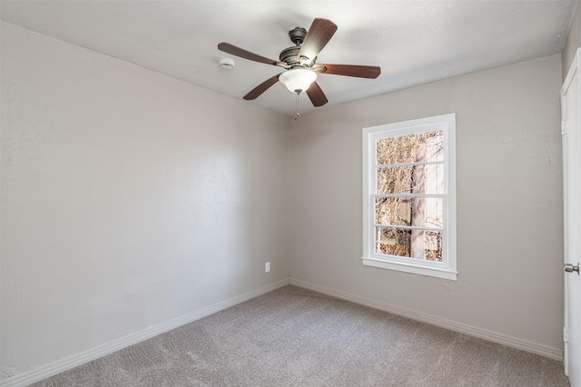 carpeted empty room featuring baseboards and a ceiling fan