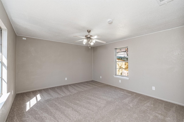 spare room featuring a textured ceiling, ceiling fan, carpet flooring, and visible vents