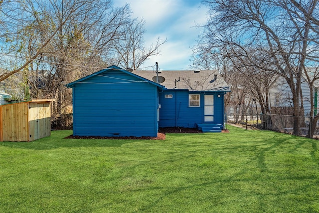 rear view of property with entry steps, fence, and a yard