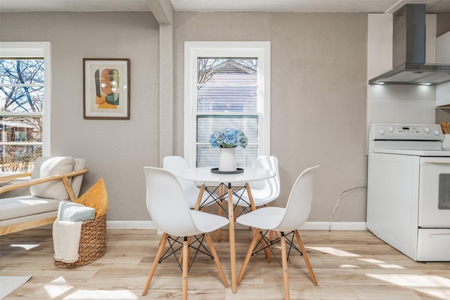 dining area with a healthy amount of sunlight, light wood-style flooring, and baseboards