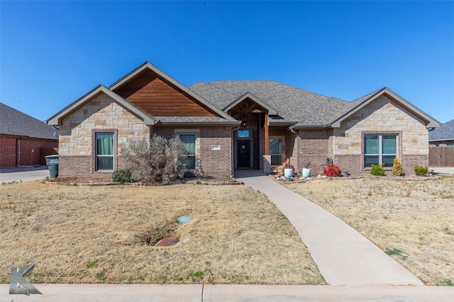 craftsman-style home featuring a shingled roof and brick siding