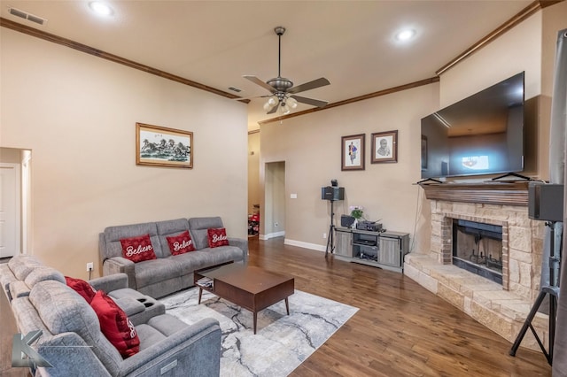 living area with crown molding, a fireplace, visible vents, wood finished floors, and baseboards