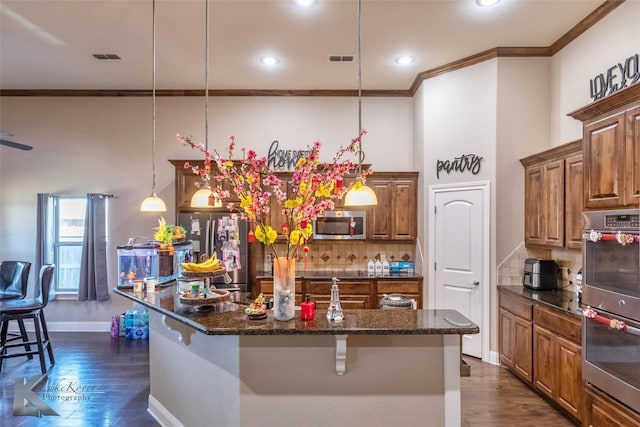 kitchen featuring dark wood-style flooring, appliances with stainless steel finishes, brown cabinetry, and crown molding