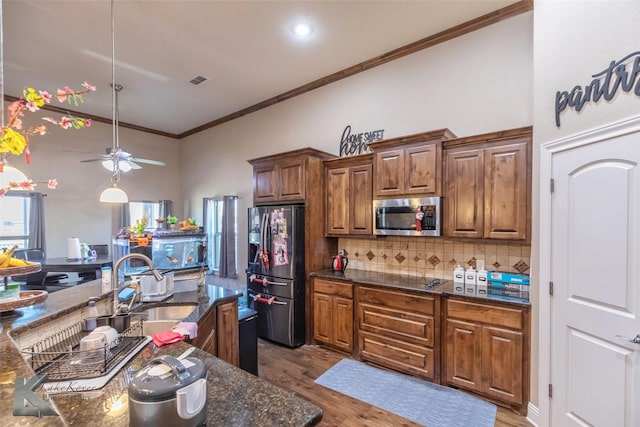 kitchen featuring tasteful backsplash, appliances with stainless steel finishes, ornamental molding, wood finished floors, and a sink