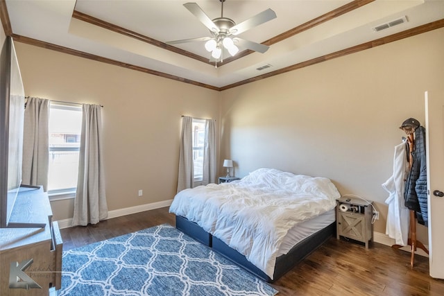 bedroom with a tray ceiling, visible vents, and crown molding