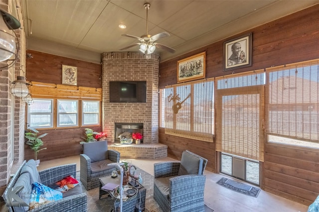 sunroom featuring a brick fireplace and a ceiling fan