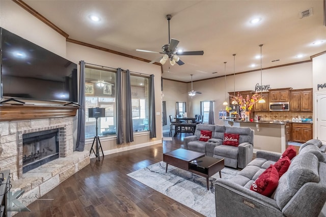 living room featuring ceiling fan, a fireplace, visible vents, ornamental molding, and dark wood-style floors