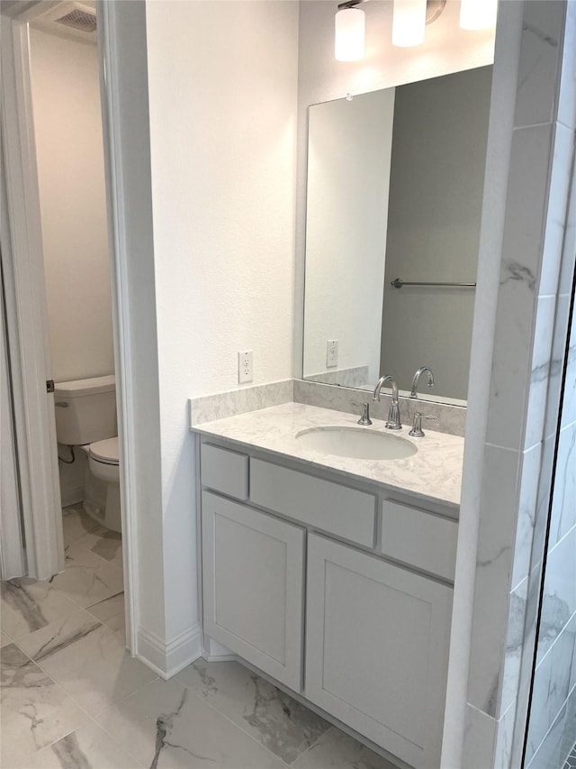 bathroom featuring marble finish floor, baseboards, vanity, and toilet