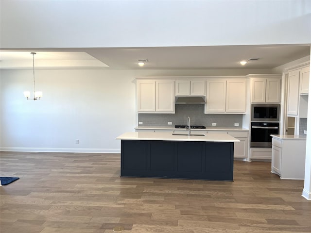 kitchen with light countertops, oven, stainless steel microwave, and under cabinet range hood