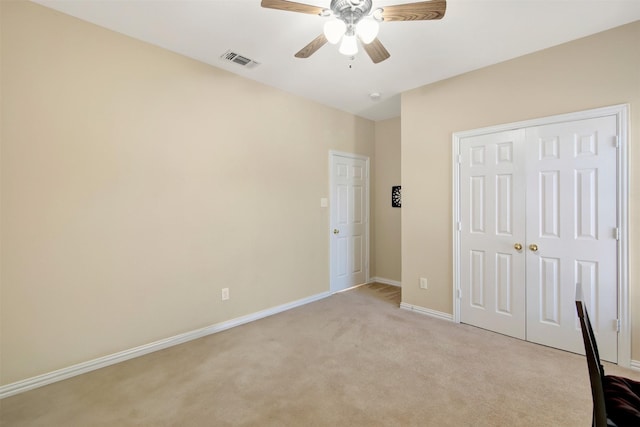 unfurnished bedroom with baseboards, visible vents, light colored carpet, ceiling fan, and a closet