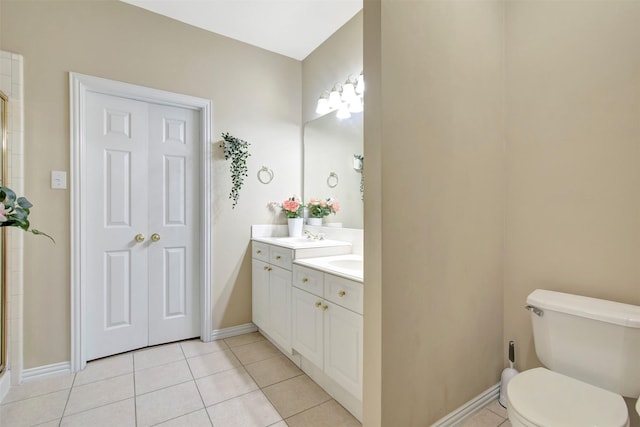 bathroom with a shower with shower door, vanity, toilet, and tile patterned floors