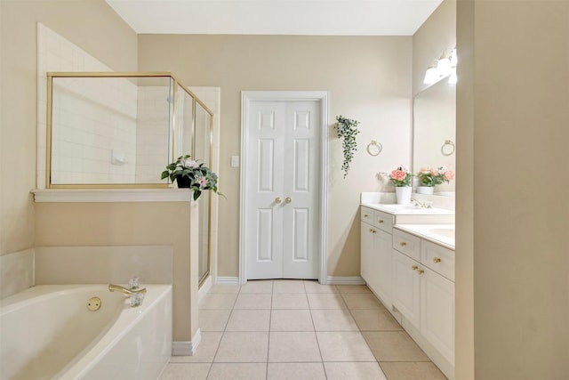 full bathroom with a garden tub, a shower stall, vanity, tile patterned flooring, and baseboards