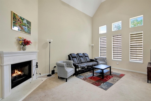 living area featuring carpet floors, a warm lit fireplace, baseboards, and high vaulted ceiling