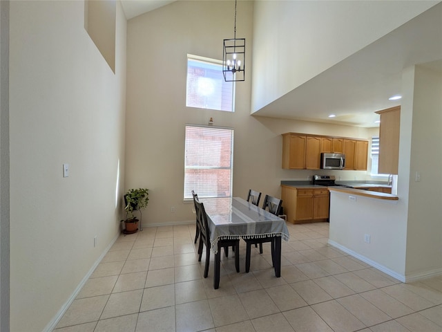 dining area featuring recessed lighting, a towering ceiling, light tile patterned flooring, a chandelier, and baseboards