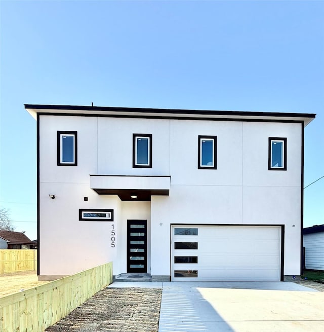 view of front of property with a garage, driveway, fence, and stucco siding