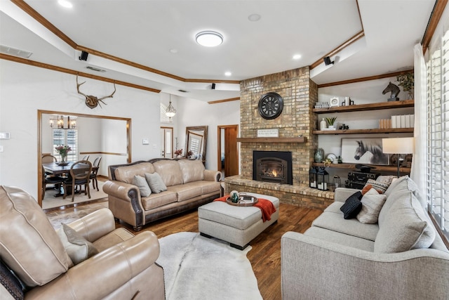 living area with a fireplace, visible vents, wood finished floors, and ornamental molding