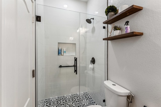 bathroom with a textured wall, a shower stall, and toilet