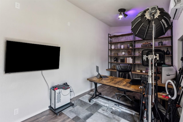 office area with a wall unit AC, wood finished floors, and baseboards