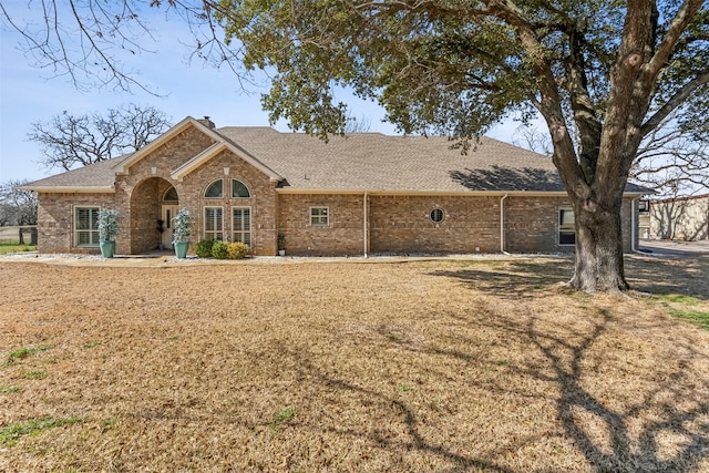 view of front of property with brick siding and roof with shingles