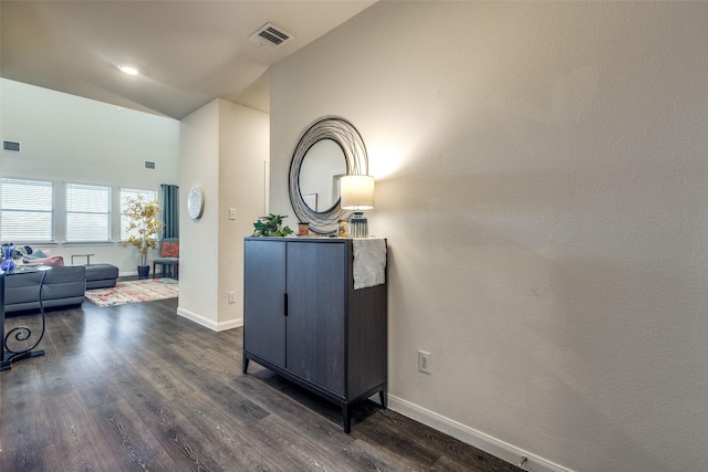 hallway with dark wood-type flooring, visible vents, and baseboards