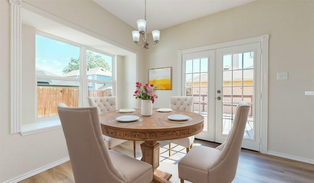 dining area featuring a notable chandelier, baseboards, wood finished floors, and french doors