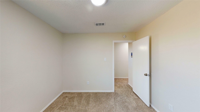 spare room with a textured ceiling, carpet floors, visible vents, and baseboards