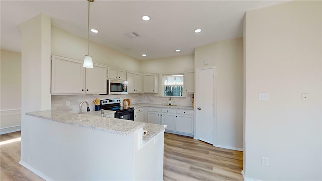 kitchen featuring a peninsula, electric range, stainless steel microwave, and backsplash