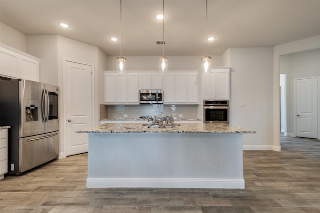 kitchen with decorative backsplash, white cabinetry, stainless steel appliances, and wood finished floors