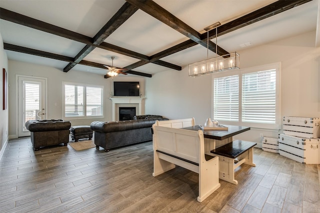 dining space with coffered ceiling, a ceiling fan, wood finished floors, beamed ceiling, and a fireplace