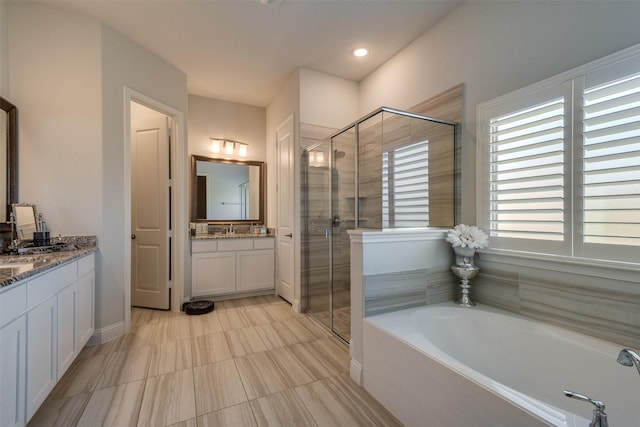 bathroom featuring two vanities, a garden tub, and a shower stall